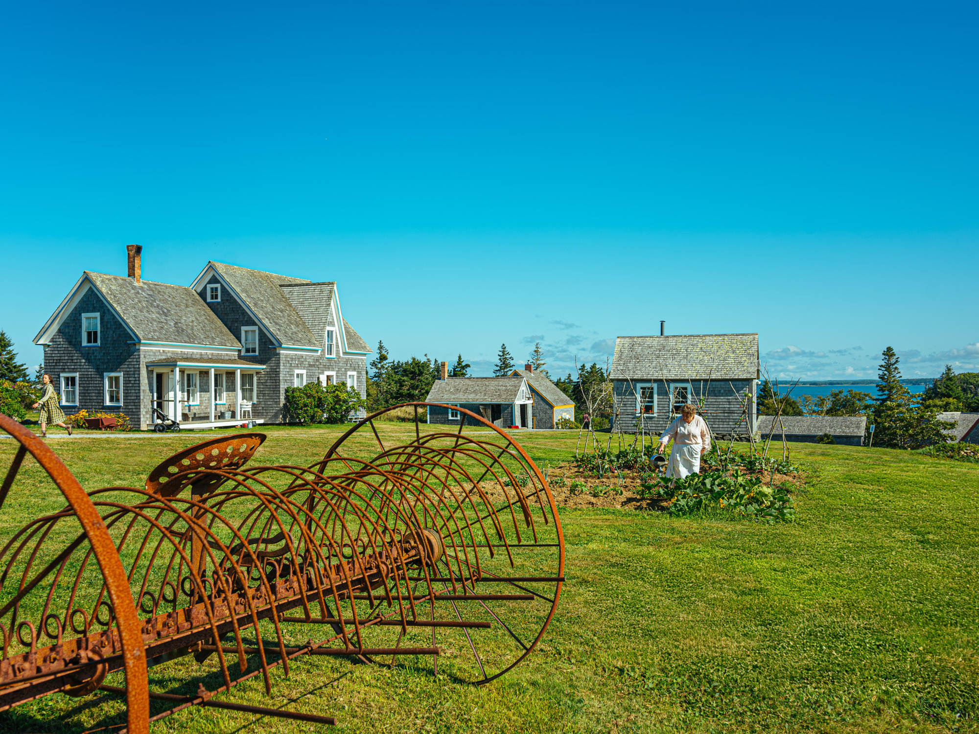Farm equipment, in a field with homes in the distance.