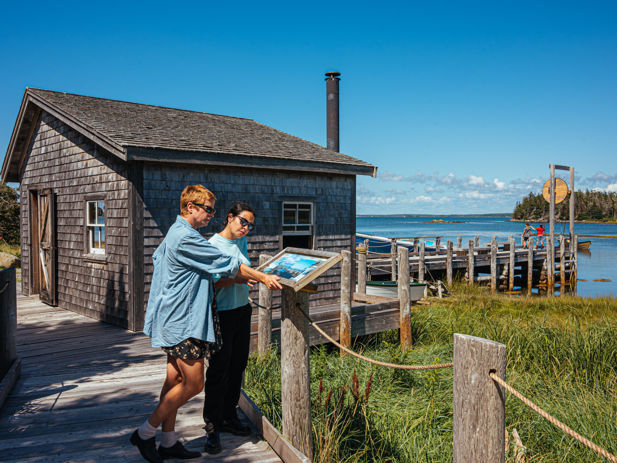 Visitor reading an outdoor interpretive panel at the Historic Acadian Village of Nova Scotia