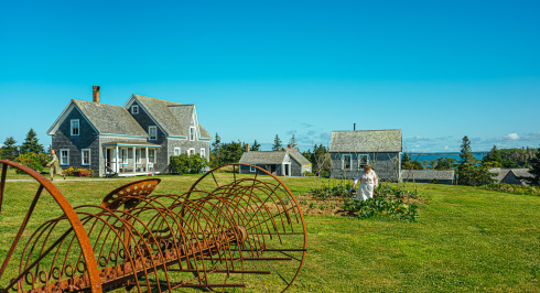 Farm equipment, in a field with homes in the distance.