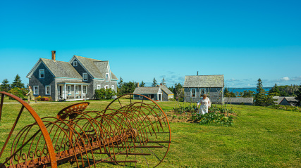 A field with farm equipment and home in the background.